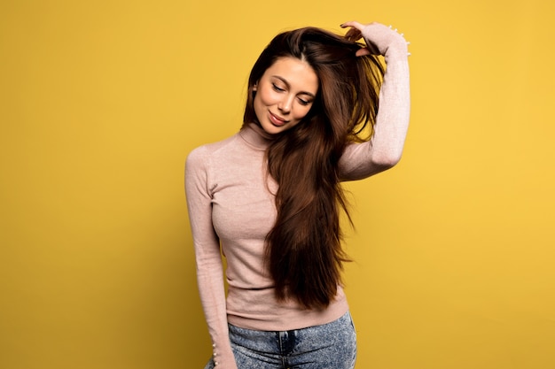 pacified girl in pink pullover straightens her hair