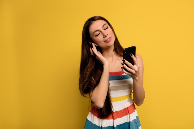 pacified girl with closed eyes listening music in headphones wearing bright dress