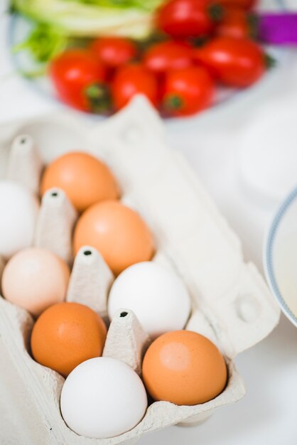 Пакет яиц на кухонном столе с овощами