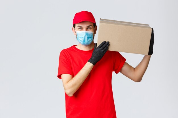 Packages and parcels delivery, covid-19 quarantine delivery, transfer orders. Friendly courier bring order to client house, holding package box on shoulder, wear face mask and rubber gloves