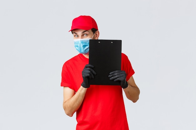 Free photo packages and parcels delivery, covid-19 quarantine delivery, transfer orders. friendly courier in carrier service bring order to doorstep, holding clipboard with sign form, wear face mask and gloves