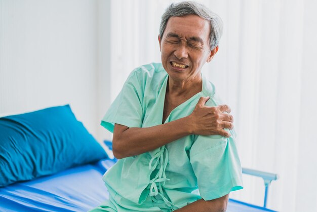 통증과 어깨 통증 환자 제복을 입은 아시아 수석 할아버지는 신체 문제 건강 아이디어 개념으로 고통받습니다.