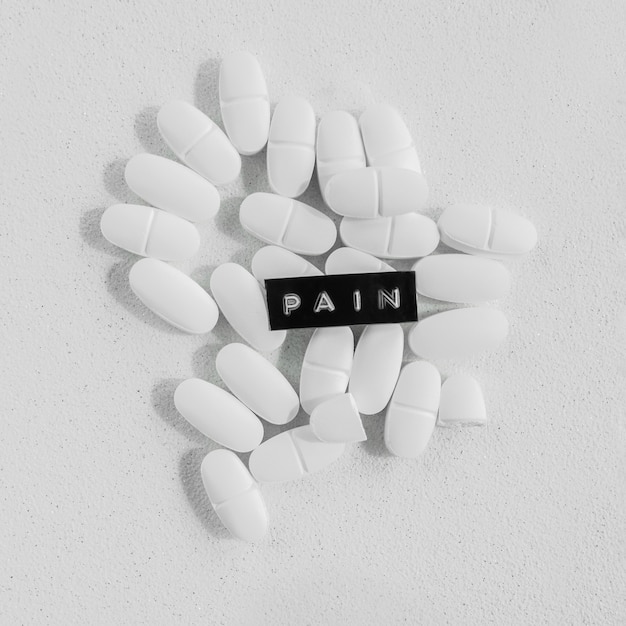 Pain text over the white tablets on the rough background