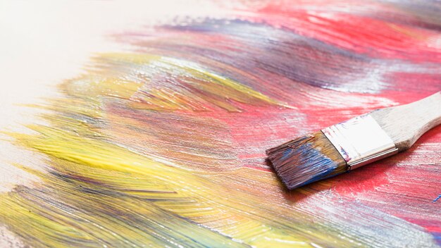 Paint brush on messy colorful brushstroke on surface