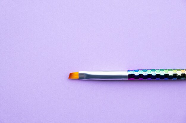 Paint brush on purple paper background.