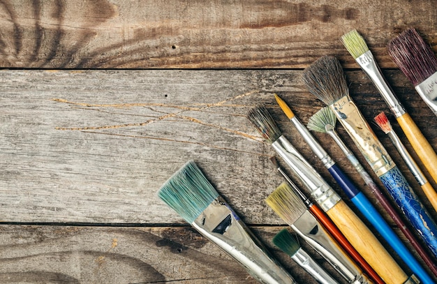 Paint brushes of different sizes on a wooden background flat lay