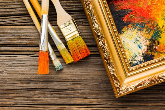 Paint brushes and painted canvas in frame