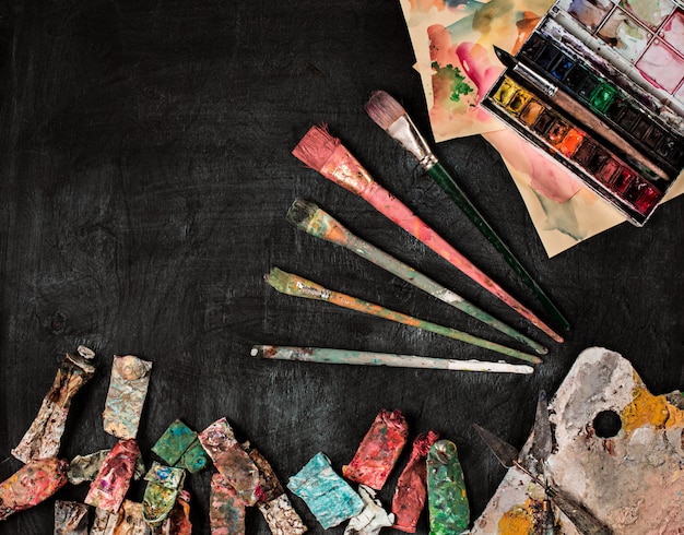Paint brushes and tubes of oil paints on wood