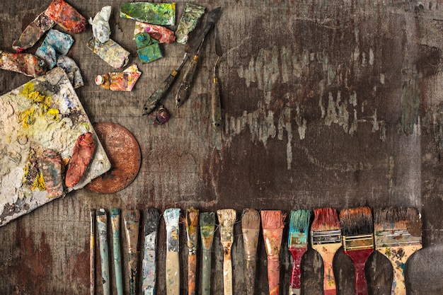 Paint brushes and tubes of oil paints on wooden table