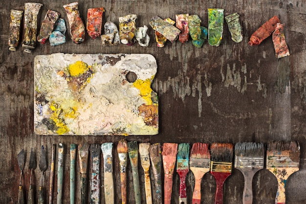 Paint brushes and tubes of oil paints on wooden table