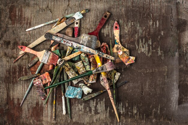 Paint brushes and tubes of oil paints on wooden table