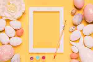 Free photo paint color; paintbrush; white border frame; rose and easter eggs on yellow backdrop