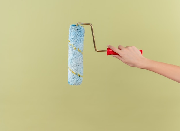 Free photo paint roller on isolated green wall