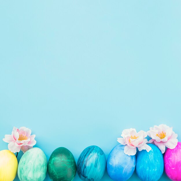 Painted eggs with flowers on blue background