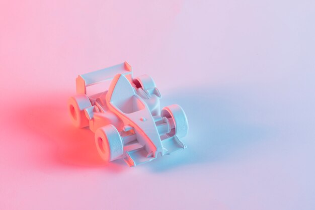 Painted miniature formula one car against pink background