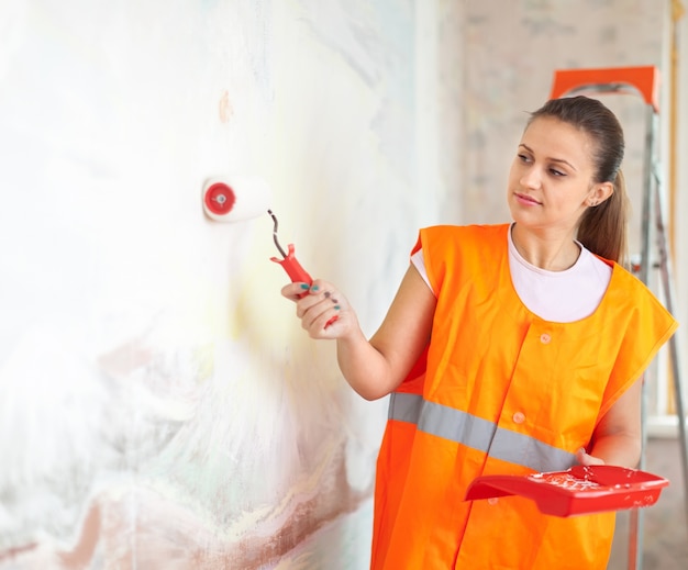 Free photo painter paints wall with roller