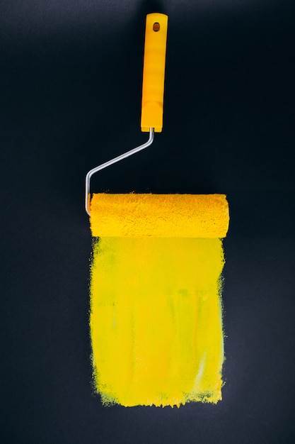 노란색 페인트에서 검은 배경에 고립 된 수리 용 Paintroller
