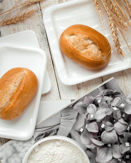 A pair of bread buns and wheat branches