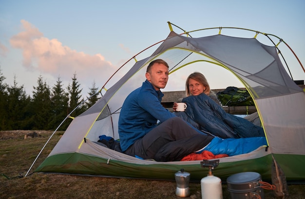 Pair of campers relaxing in tent outdoors