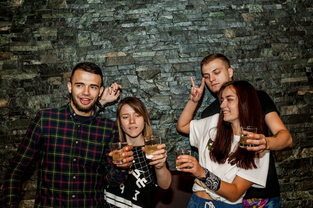 Pair of couple holding cocktail standing against wall