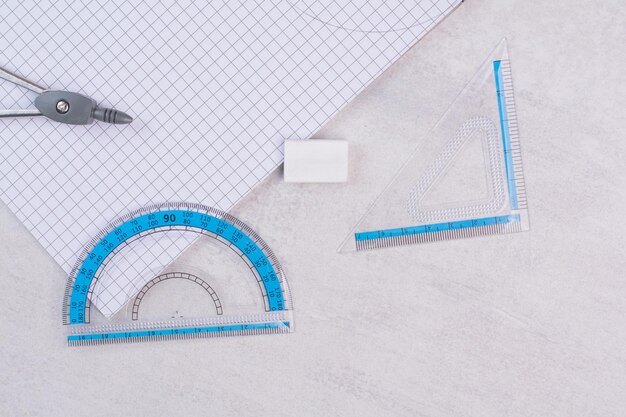 Free photo pair of geometry compasses and paper on white table.