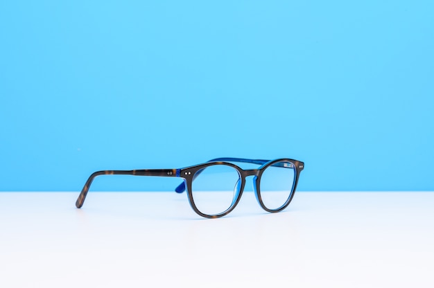 青い背景と白い表面上のメガネのペア