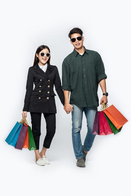 A pair of man and woman wearing glasses and carried lots of paper bags for shopping