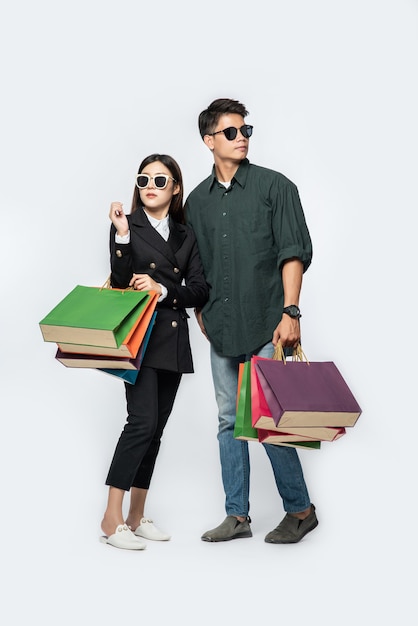 A pair of man and woman wearing glasses and carried lots of paper bags for shopping