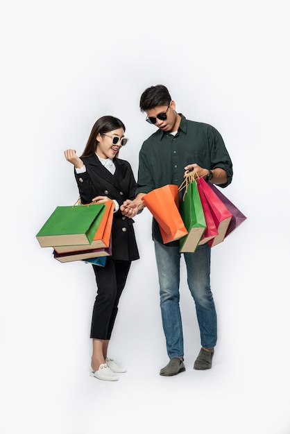 한 쌍의 남녀가 안경을 쓰고 쇼핑을 위해 많은 종이 봉지를 들고