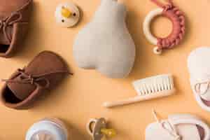 Free photo pair of shoes; pacifier; stuffed pear; brush; milk bottle on an orange backdrop