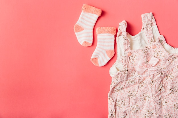 Pair of sock and baby dress on bright colored background