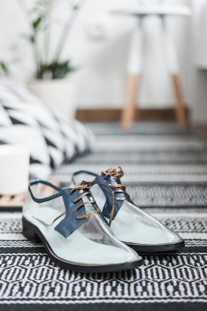 Pair of trendy transparent shoes on woven rug