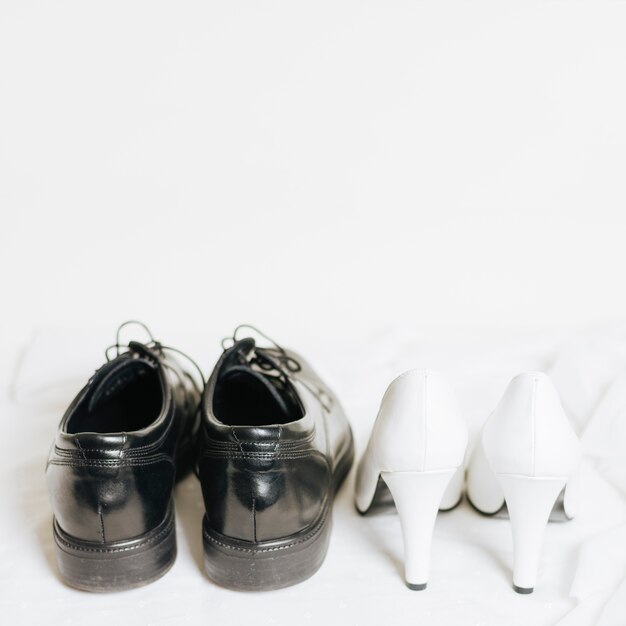 Pair of wedding high heels and black shoes on white background