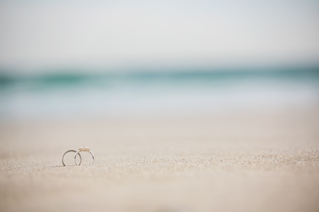 Free photo pair of wedding ring on sand