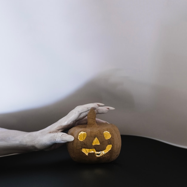 Foto gratuita jack-o-lanterna toccante a mano pallida