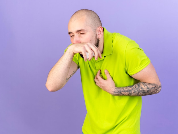 Free photo pale young caucasian ill man holds hand close to nose on purple