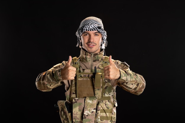 Palestinian serviceman in military uniform smiling on black wall