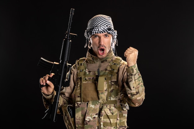 Палестинский военнослужащий в военной форме с винтовкой на темной стене