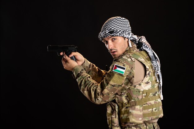 Palestinian soldier aiming gun on a black wall