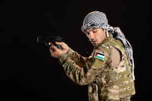 Free photo palestinian soldier aiming gun on the black wall