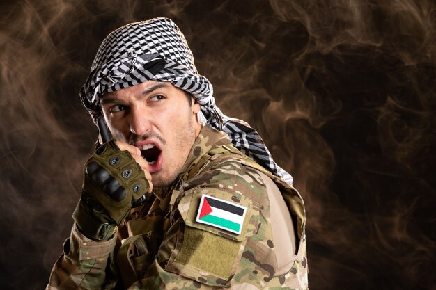 Палестинский солдат разговаривает по рации на темной стене