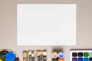 Free photo palette and brushes near paints and paper