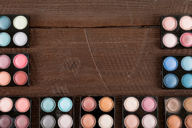 Palette of various eye shadow powder on wooden backdrop