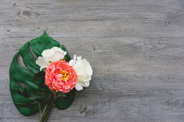 Palm leaf and flowers on wooden surface