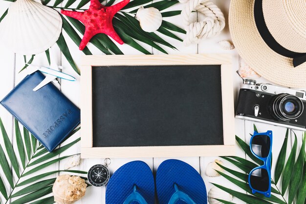 Palm leaves and travel supplies around blackboard