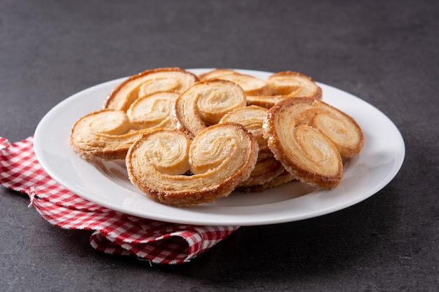 Free photo palmier puff pastry in plate on black slate background