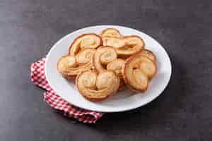 Free photo palmier puff pastry in plate on black slate background