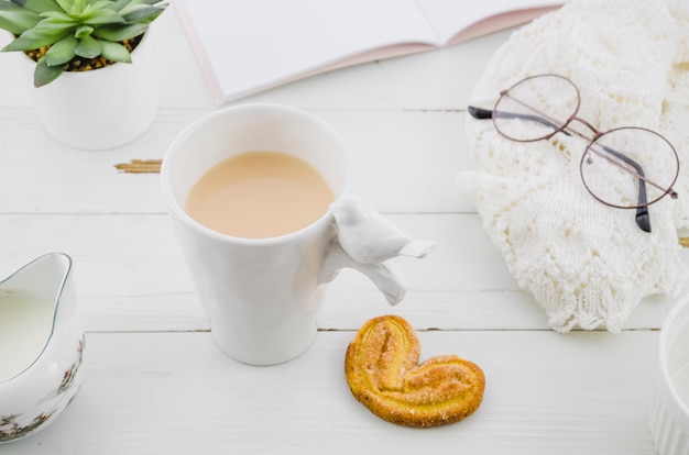 Palmiers or elephant ear puff pastry cookie with porcelain white tea cup on wooden desk