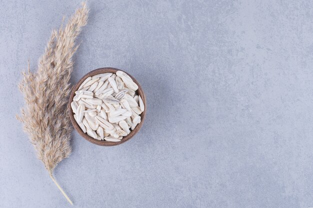 Pampas grass and bowl of sunflower seeds on marble.