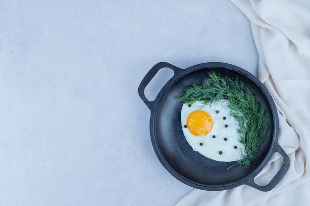 A pan of omelet with pepper and greens on white.